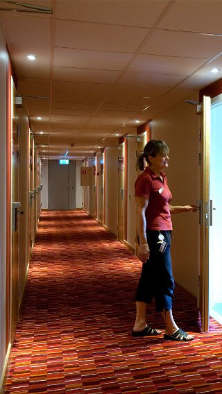 一个女人站在 Spar 酒店采用飞利浦酒店照明的走廊中