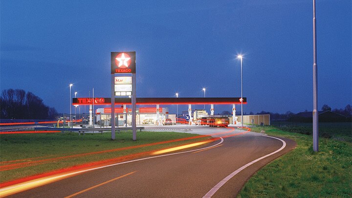 傍晚时分，高速公路旁一家 Texaco 加油站的照明引人注目 - 引人注目的户外照明