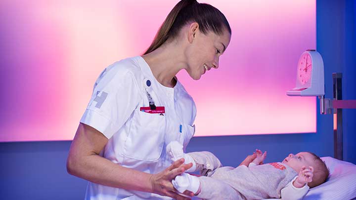 一位护士正在灯光柔和的病房内为婴儿称重 - 医疗照明