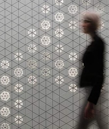 一位女士步行经过饰有飞利浦 Luminous Patterns 的内墙 - 消费者体验