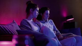 飞利浦 Hue 智能 LED 灯在客厅中营造出鲜艳的紫色和粉红色氛围，展示适合现代家庭中的电影之夜和休闲放松的可定制氛围照明。