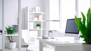 一间明亮的白色房间里，一张书桌上放着一台电脑和一盏桌灯。